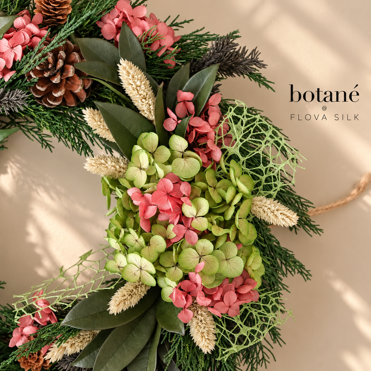 Close-up of Botané Christmas Bloom wreath with preserved pink hydrangeas, pine cones, evergreen foliage and dried grasses by FLOVA SILK.