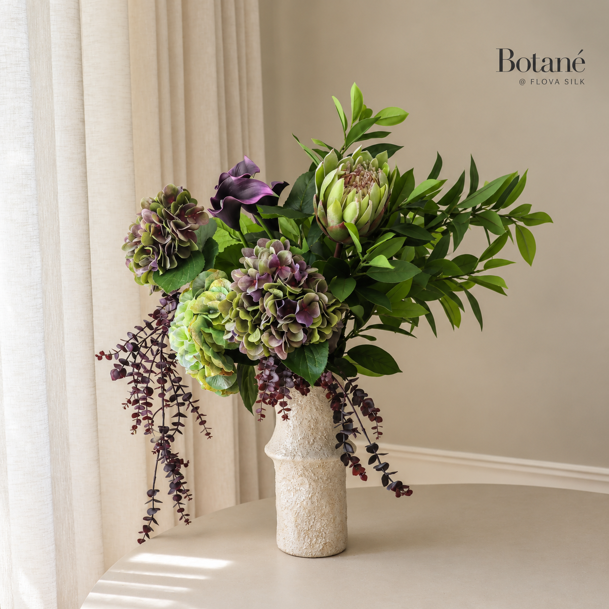 Aubergine Bloom luxury artificial flower arrangement by Botané at FLOVA SILK with deep purple calla lilies, mauve hydrangeas, green protea and cascading foliage.